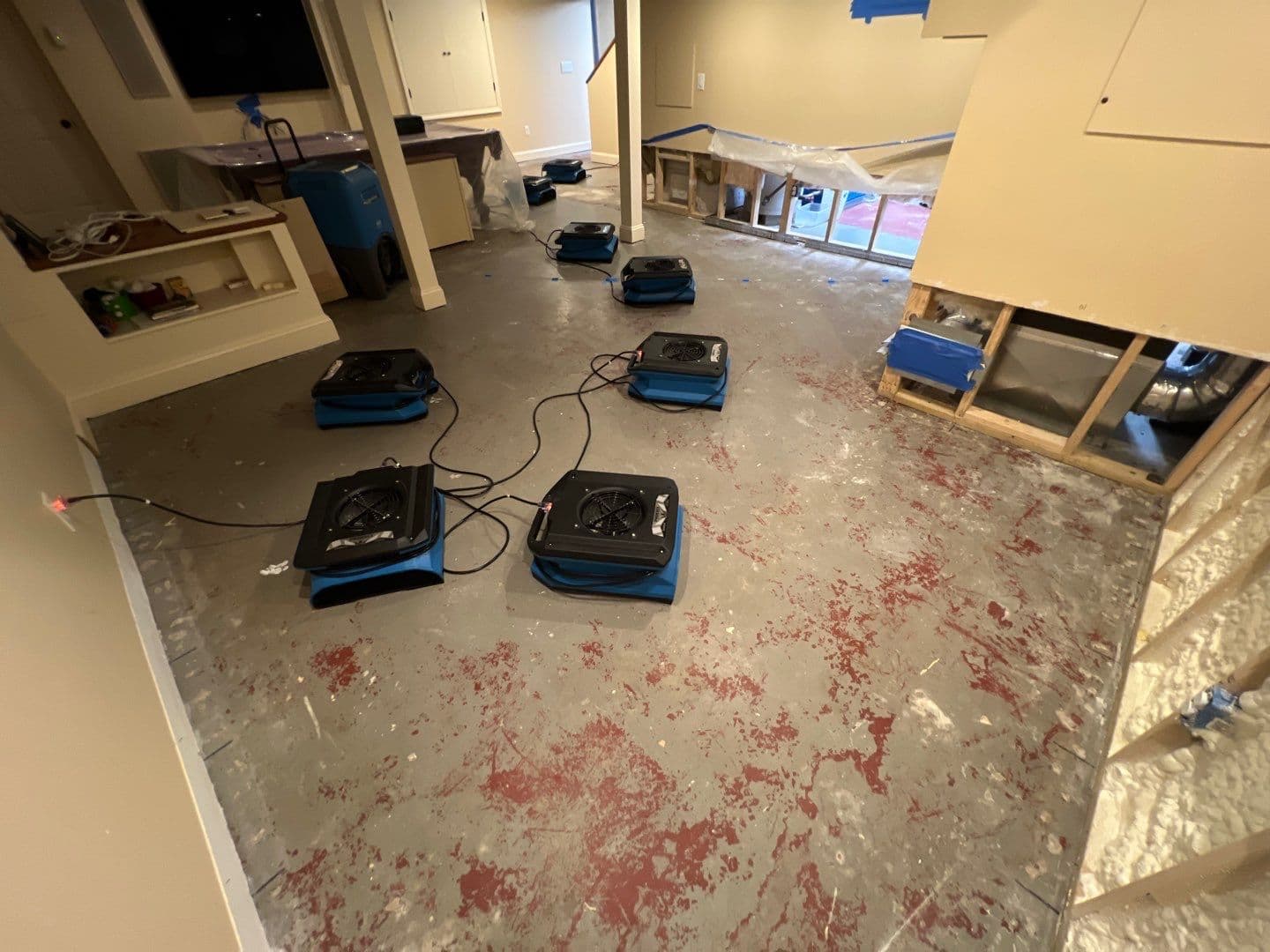 Air movers set up in a basement after water-damaged wall materials were removed for structural drying