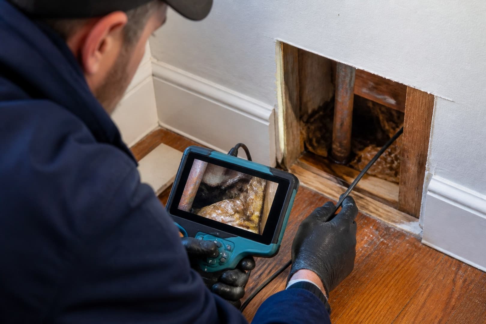BRG technician inspecting a concealed wall area for moisture behind a musty odor — close technical detail